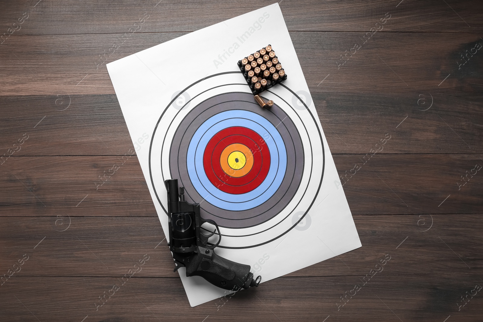 Photo of Shooting target, handgun and bullets on wooden table, top view