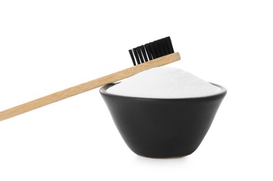 Bamboo toothbrush and bowl with baking soda on white background