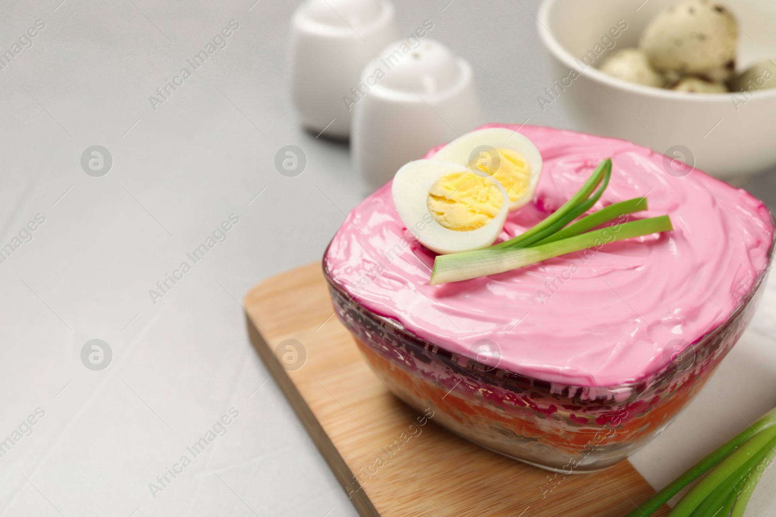 Photo of Herring under fur coat salad on white table, closeup with space for text. Traditional Russian dish