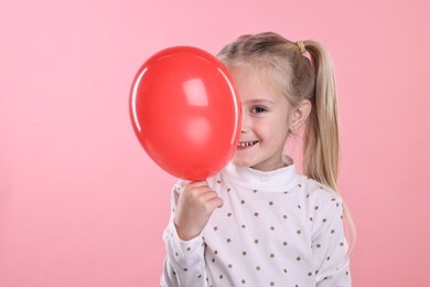Photo of Cute little girl with red balloon on pink background, space for text