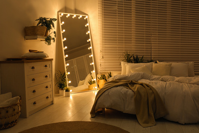 Photo of Stylish mirror with light bulbs in dark bedroom. Interior design