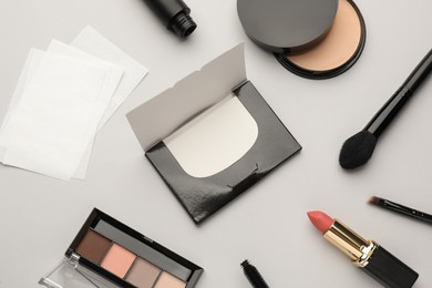 Photo of Flat lay composition with facial oil blotting tissues and makeup products on light grey background. Mattifying wipes