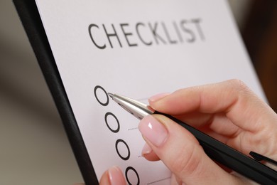 Photo of Woman filling Checklist with pen, closeup view