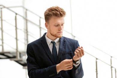 Photo of Portrait of handsome young man in elegant suit with wristwatch indoors