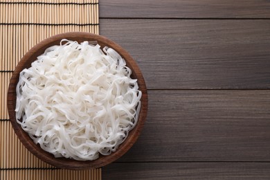 Bowl of tasty cooked rice noodles on wooden table, top view. Space for text