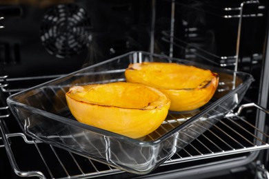 Photo of Baking dish with halves of cooked spaghetti squash in oven, closeup