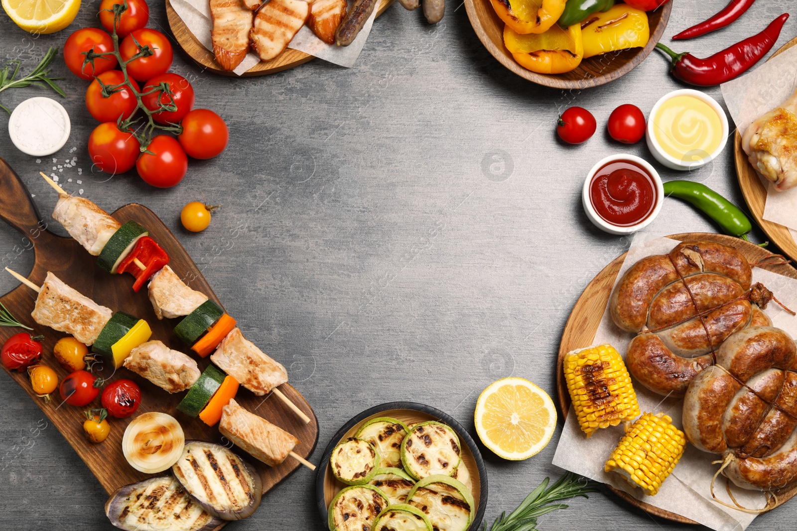 Photo of Frame of barbecued meat and vegetables on grey table, flat lay. Space for text