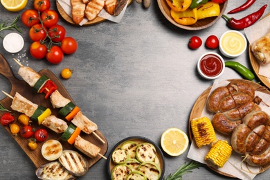 Photo of Frame of barbecued meat and vegetables on grey table, flat lay. Space for text