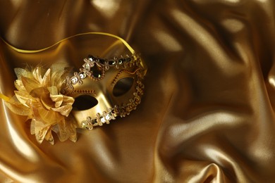 Photo of Beautifully decorated face mask on golden fabric, space for text. Theatrical performance