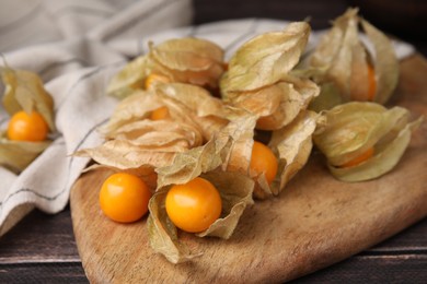 Ripe physalis fruits with calyxes on wooden table, closeup