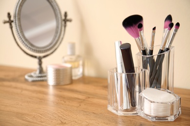 Photo of Makeup cosmetic products with tools in organizer on dressing table. Space for text