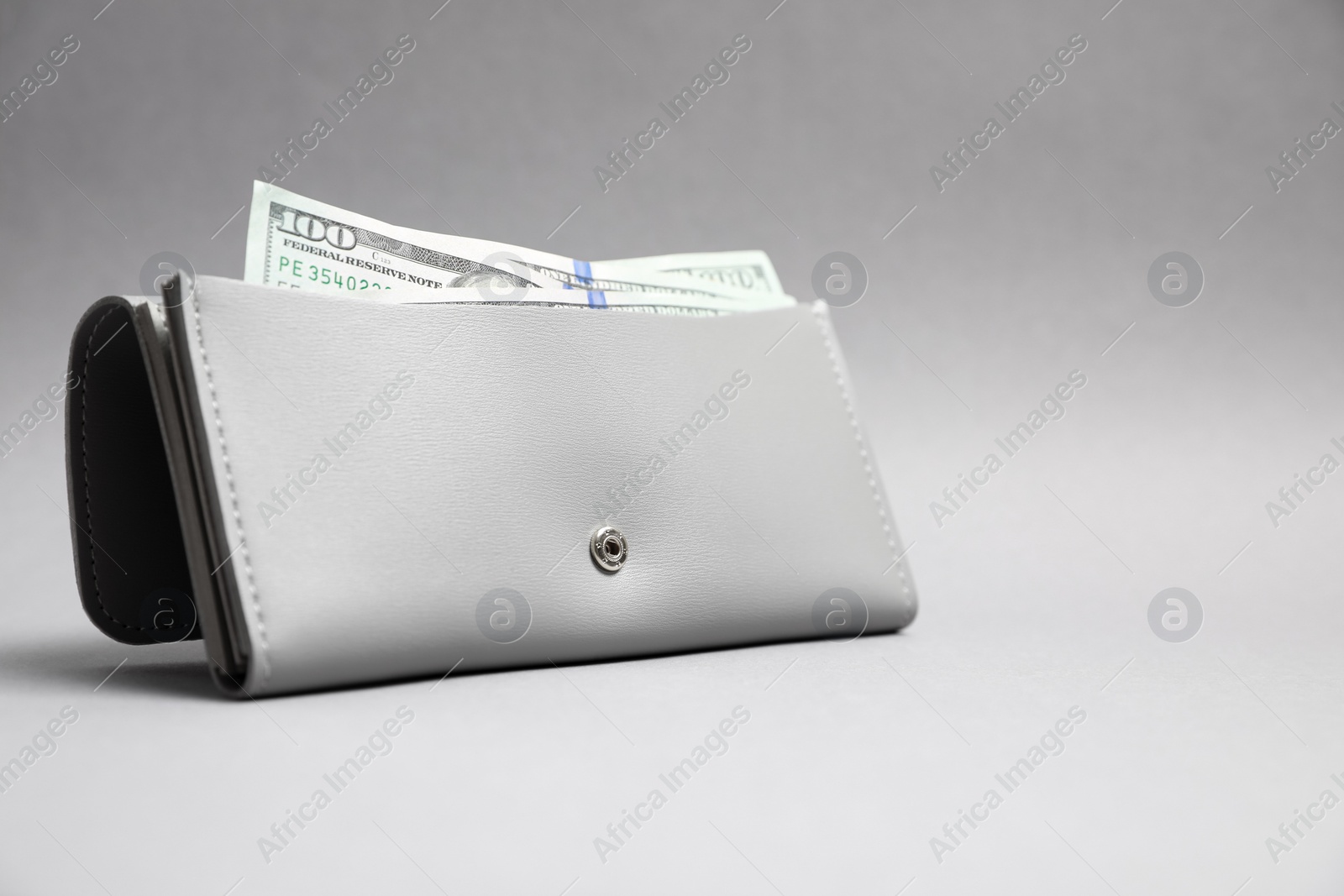 Photo of Stylish leather purse with dollar banknotes on light grey background. Space for text