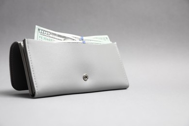 Stylish leather purse with dollar banknotes on light grey background. Space for text