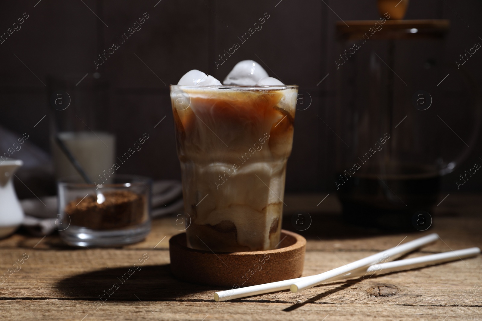 Photo of Refreshing iced coffee in glass and straws on wooden table