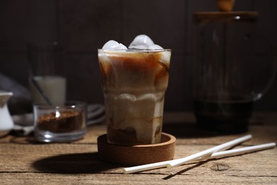 Photo of Refreshing iced coffee in glass and straws on wooden table