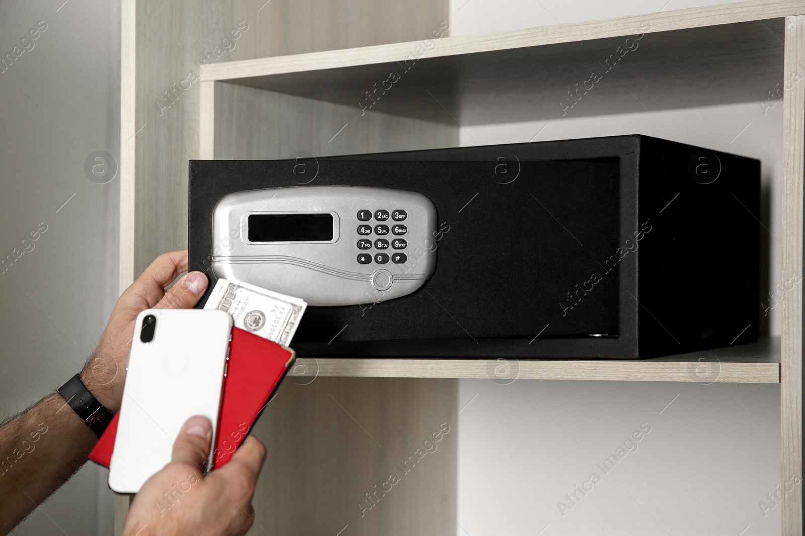 Photo of Man opening black steel safe with electronic lock at hotel, closeup