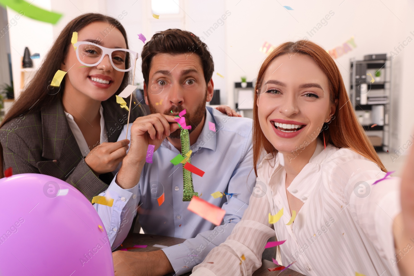 Photo of Coworkers taking selfie during office party indoors