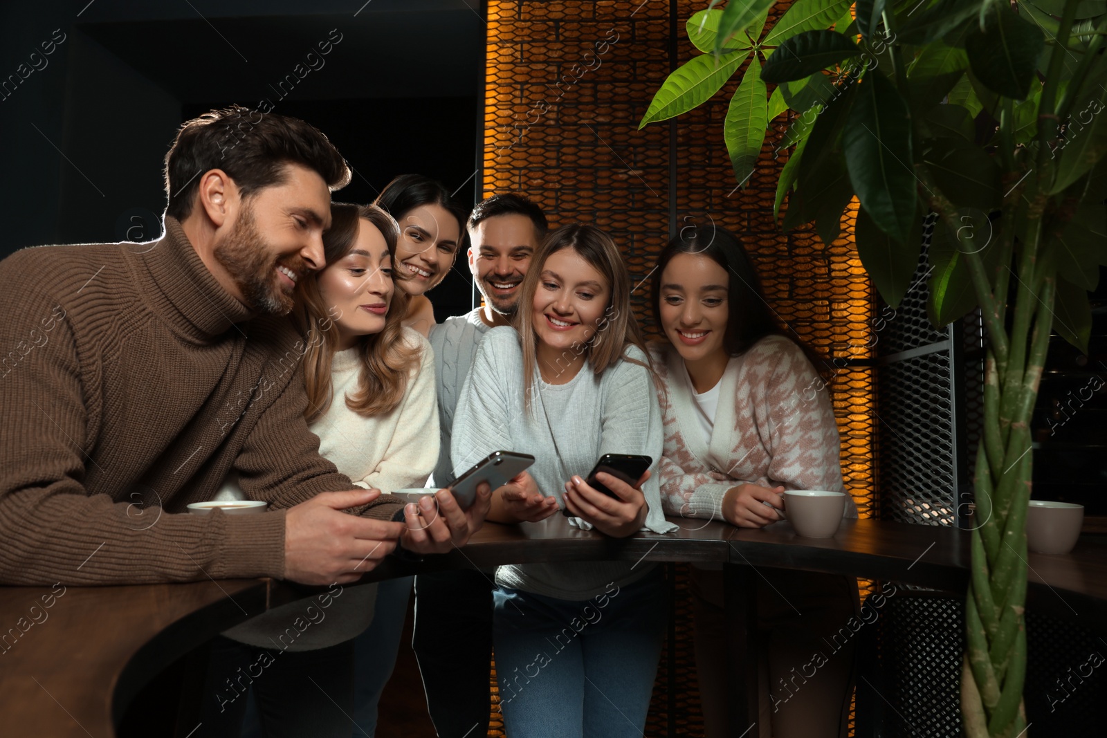 Photo of Friends with drinks and smartphones spending time together in cafe