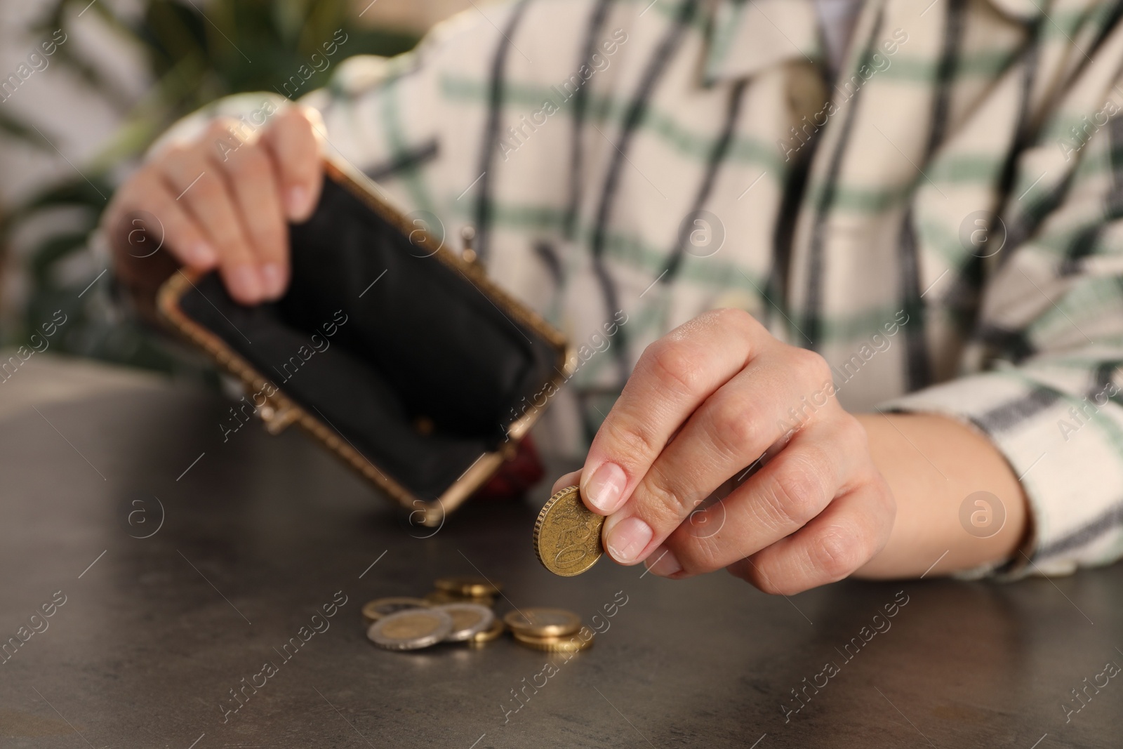 Photo of Poor woman counting coins at grey table, closeup