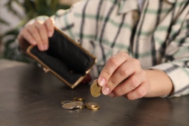 Photo of Poor woman counting coins at grey table, closeup