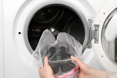 Photo of Woman putting stylish sneakers into washing machine, closeup