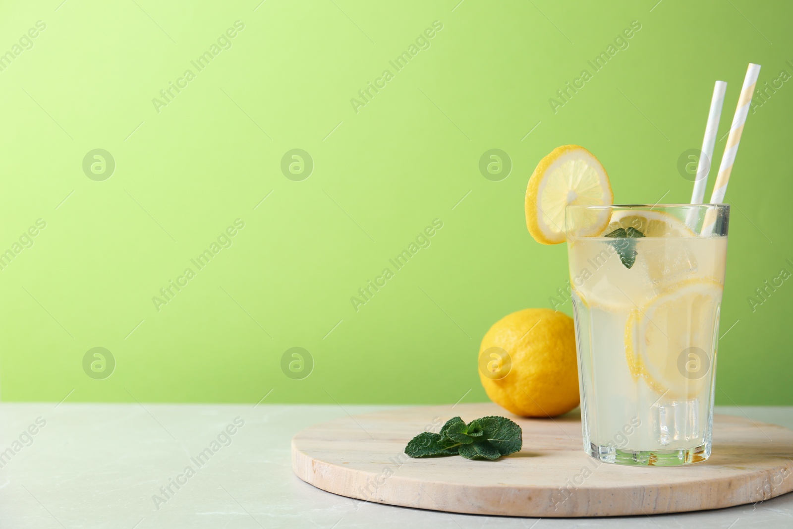 Photo of Delicious lemonade in glass on light table. Space for text