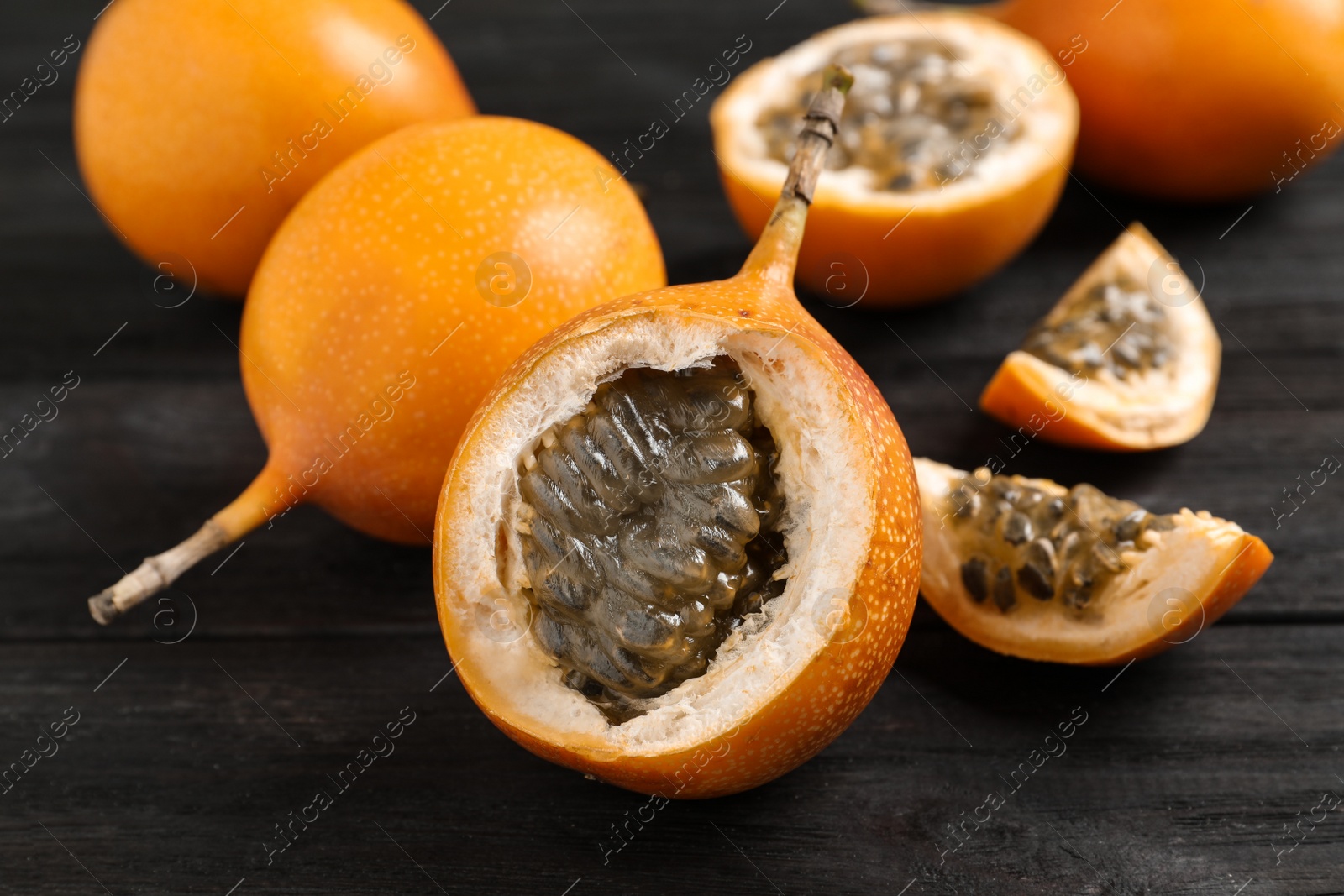 Photo of Delicious ripe granadillas on black wooden table, closeup