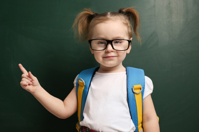 Photo of Cute little child wearing glasses near chalkboard. First time at school