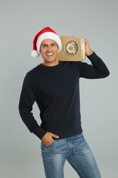 Happy man with vintage radio on light grey background. Christmas music