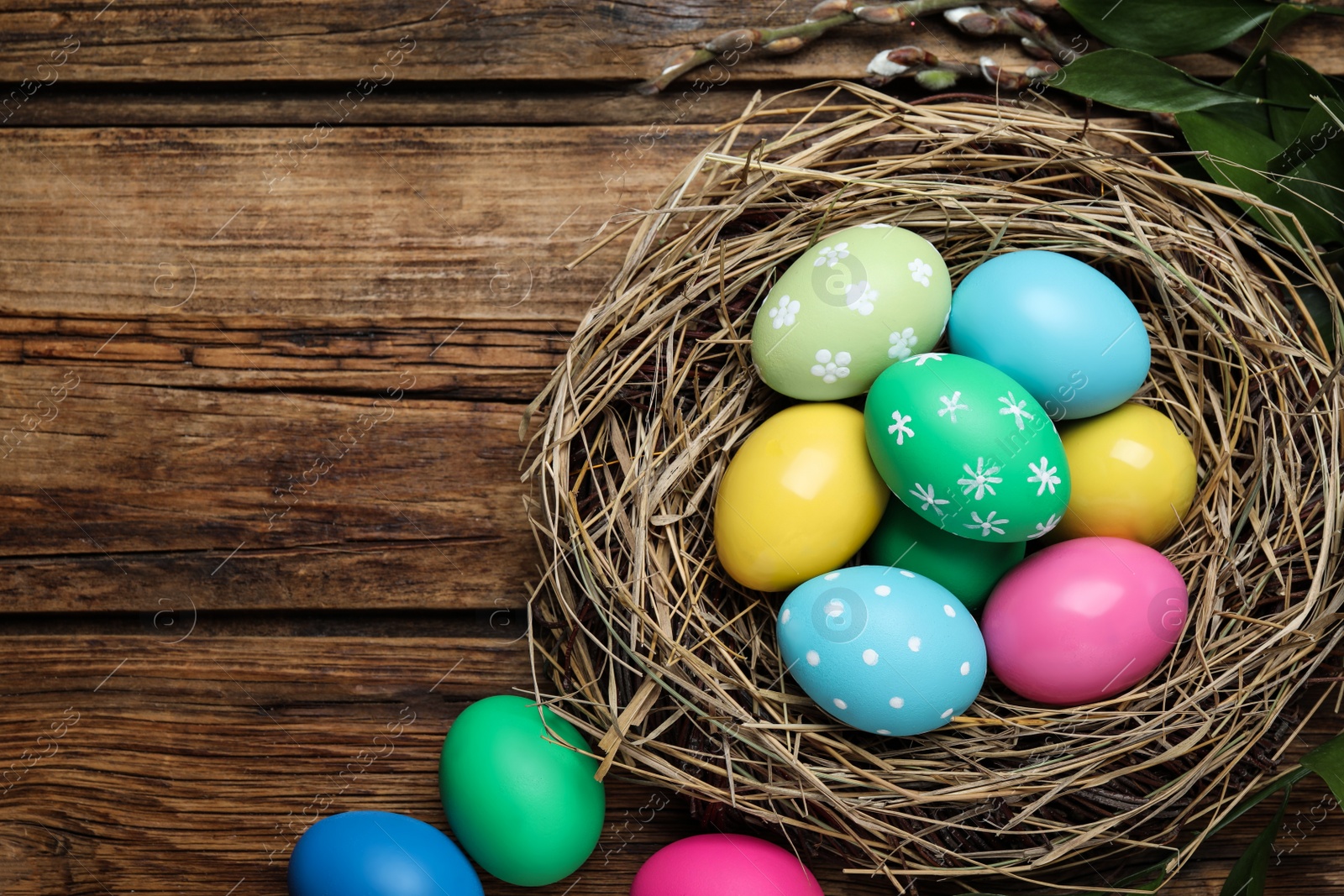Photo of Colorful eggs and nest on wooden background, flat lay with space for text. Happy Easter