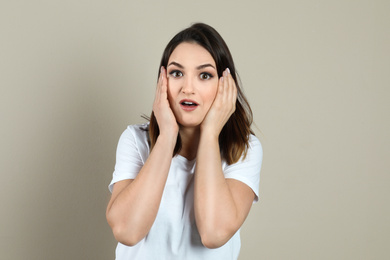 Photo of Shocked beautiful young woman on beige background