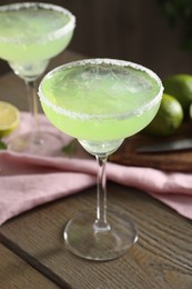 Delicious Margarita cocktail in glasses on wooden table, closeup