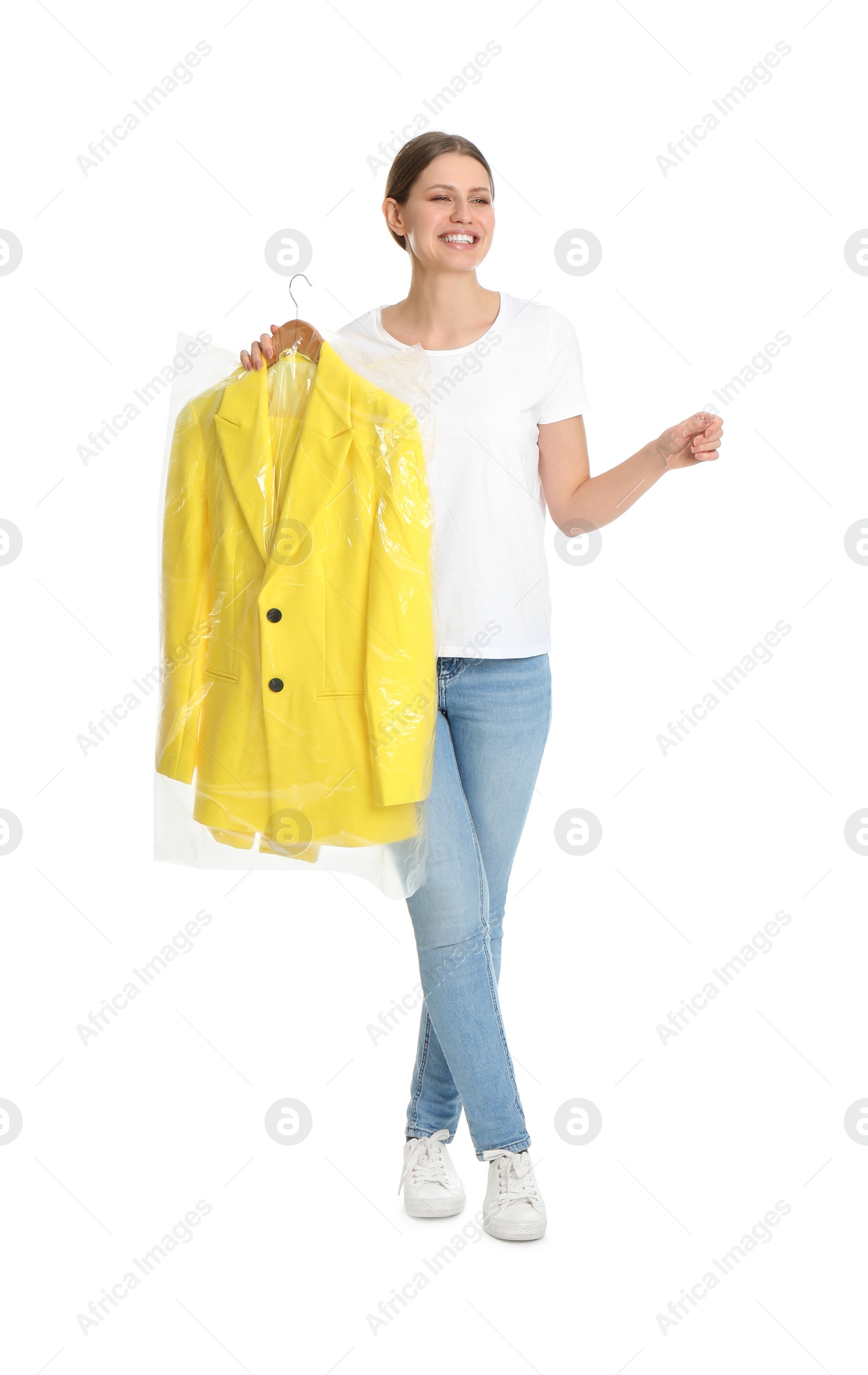 Photo of Young woman holding hanger with jacket in plastic bag on white background. Dry-cleaning service