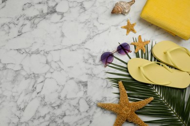 Flat lay composition with beach objects on white marble background, space for text