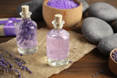 Photo of Bottles with natural herbal oil and lavender flowers on wooden background