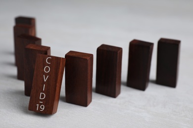 Wooden domino tiles on grey table. Spreading of coronavirus concept