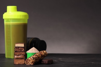 Different energy bars, protein cocktail and powder on black table. Space for text