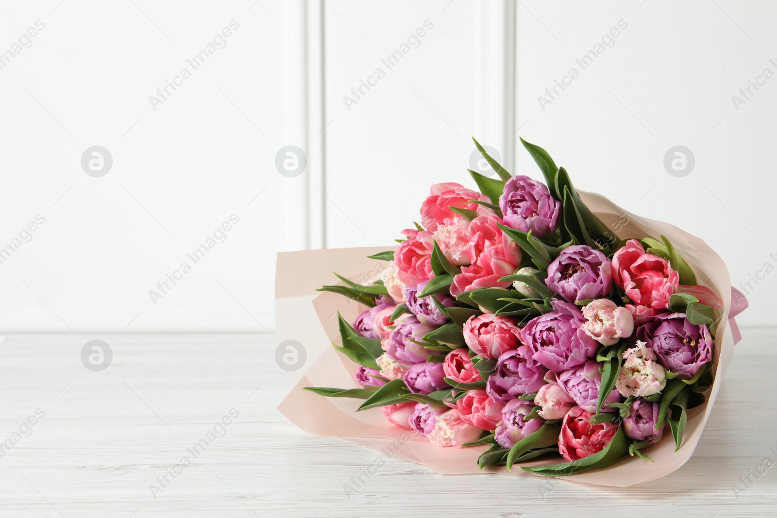 Photo of Bouquet of beautiful tulips on white wooden table. Space for text