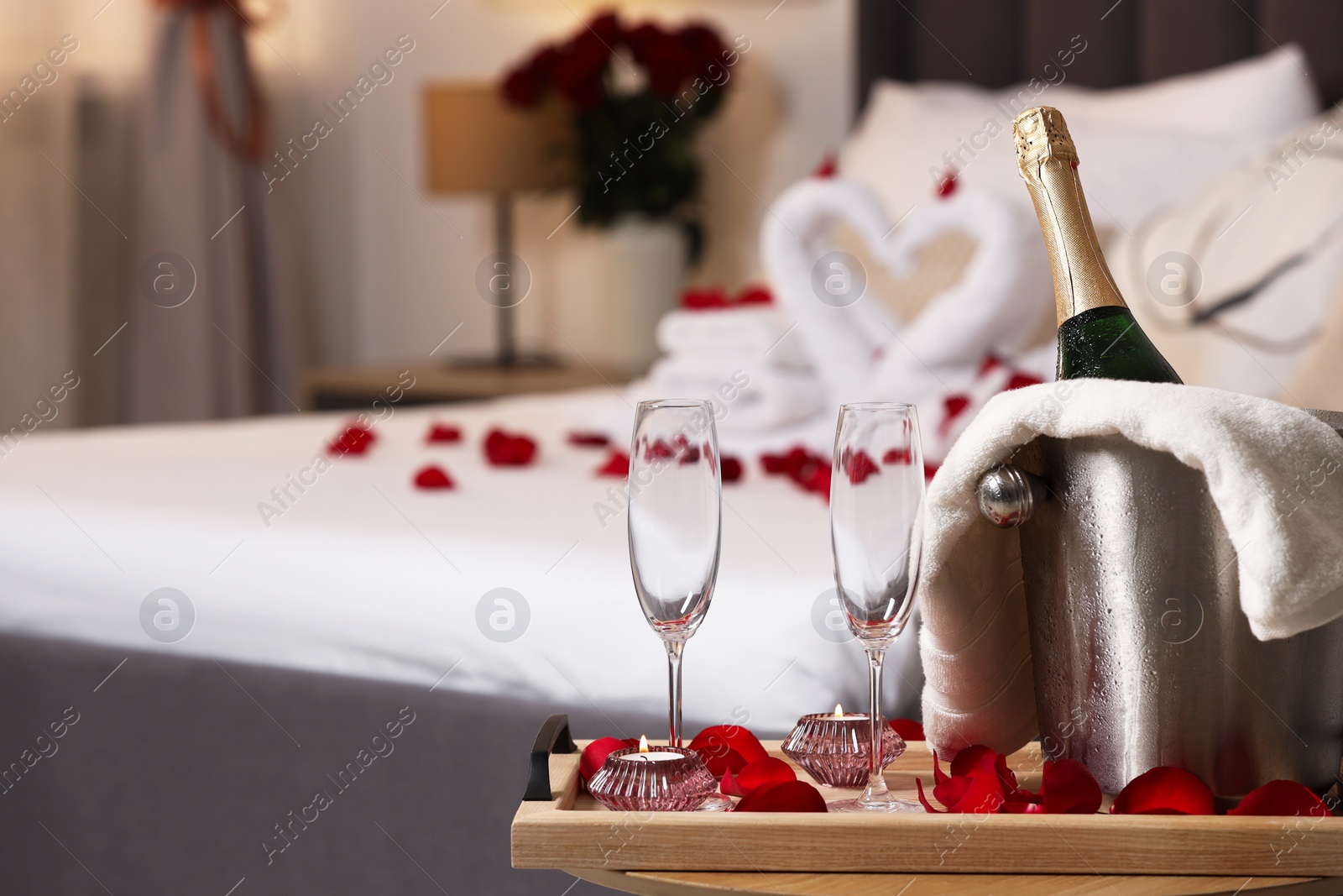 Photo of Honeymoon. Sparkling wine and glasses on wooden table in room. Space for text