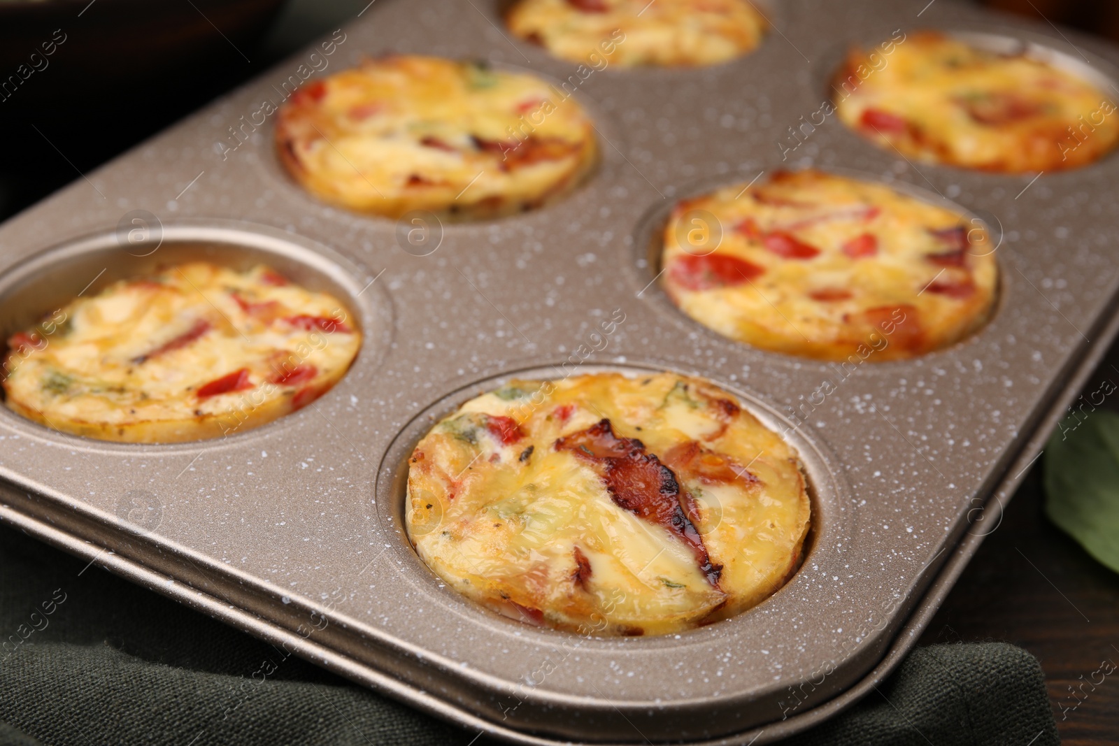 Photo of Freshly baked bacon and egg muffins with cheese in tin on table, closeup