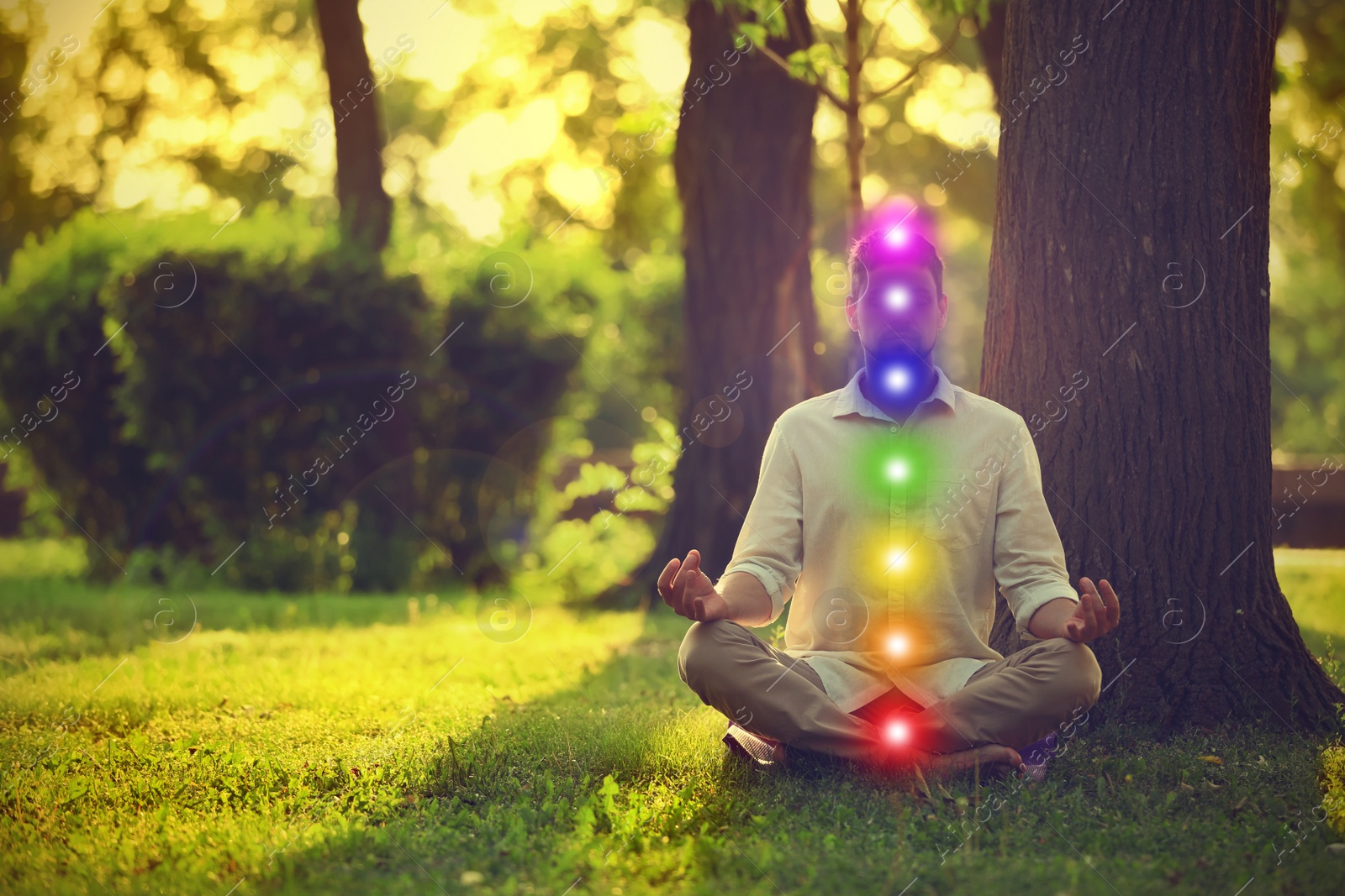 Image of Man meditating in park on sunny summer day. Scheme of seven chakras, illustration