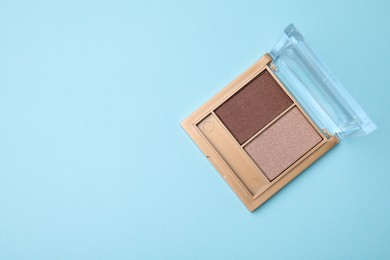 Photo of Beautiful eye shadow palette on light blue background, top view. Space for text