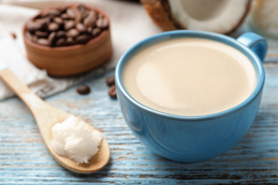 Photo of Delicious coffee with organic coconut oil on wooden table