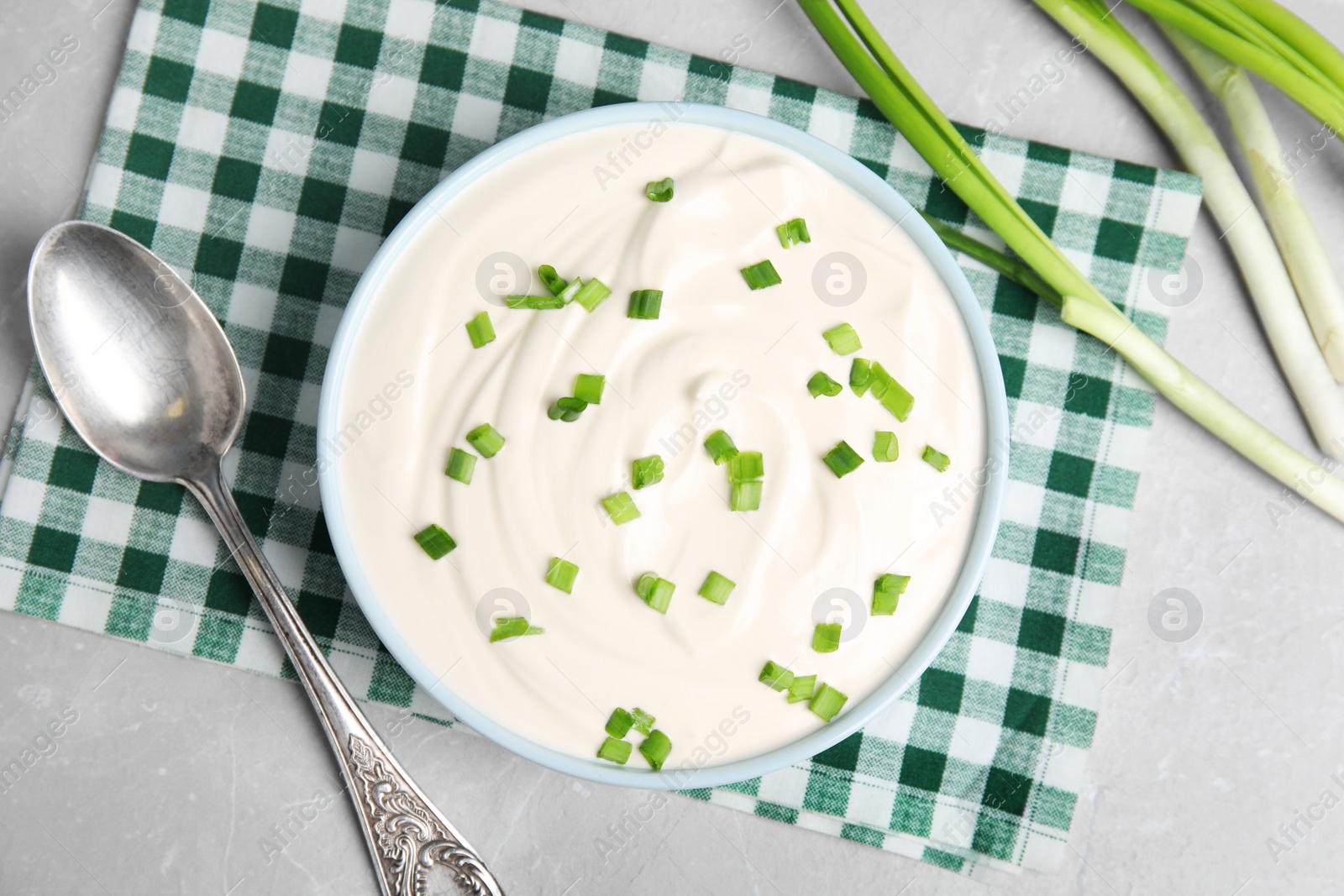 Photo of Fresh sour cream with onion on grey marble table, flat lay