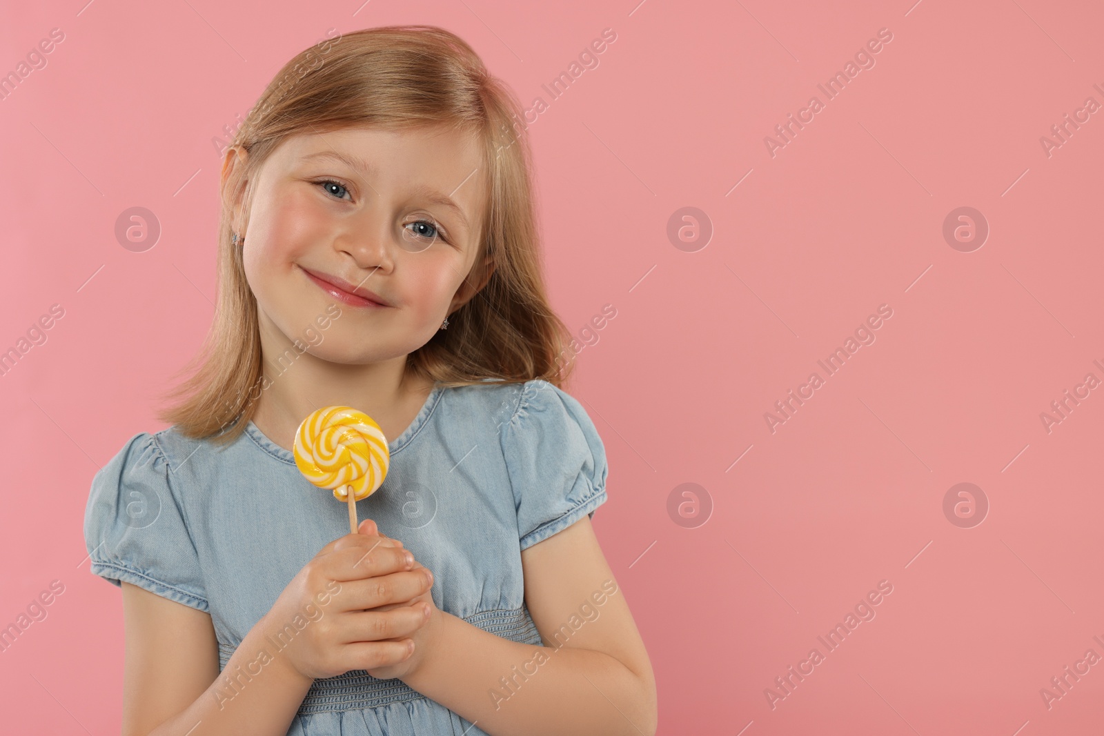 Photo of Portrait of cute girl with lollipop on pink background, space for text