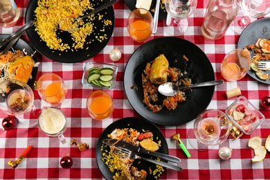 Photo of Flat lay composition of food leftovers after party on table with checkered cloth