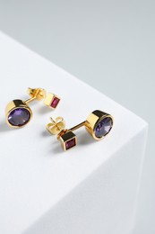 Stylish presentation of earrings on white podium, closeup