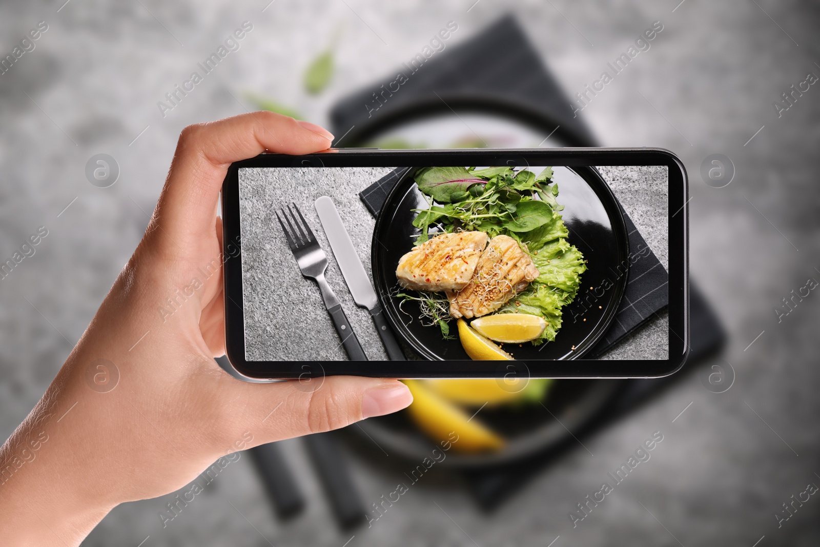 Image of Blogger taking picture of delicious grilled fish at table, closeup. Food photography