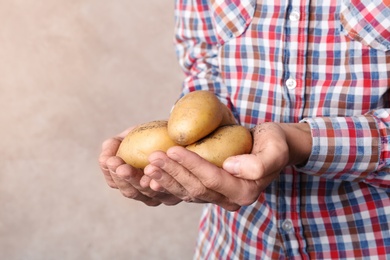 Photo of Person holding handful of fresh organic potatoes on color background