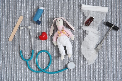 Flat lay composition with toy bunny and medical items on fabric. Children's doctor